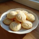 A white plate piled high with freshly baked 3-ingredient butter cookies, lightly dusted with sugar.