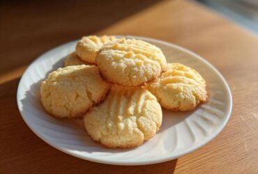 A stack of golden 3-ingredient butter cookies with fork marks on a white plate.