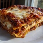 A close-up, appetizing slice of baked lasagna showing layers of pasta, rich meat sauce, and melted cheese.