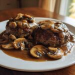 Two perfectly cooked Salisbury steak patties smothered in rich mushroom gravy and sliced mushrooms.