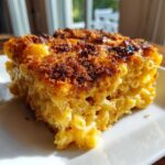A close-up of a square serving of creamy baked mac and cheese recipe with a crispy, browned breadcrumb topping.