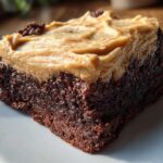 Close-up of a fudgy banana bread brownies square topped with thick peanut butter frosting.