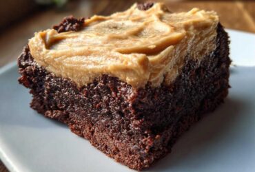 Close-up of a fudgy banana bread brownies square topped with thick peanut butter frosting.