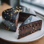 A slice of rich, dark chocolate Capricorn cake with a glossy galaxy mirror glaze and gold star sprinkles.
