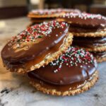 Close-up of stacked caramel Ritz cracker Christmas cookies topped with melted chocolate and festive sprinkles.