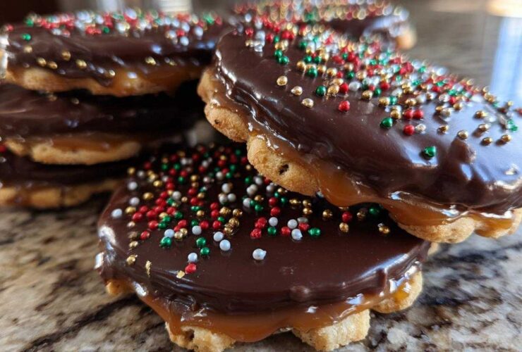Close-up of stacked caramel ritz cracker christmas cookies topped with chocolate glaze and holiday sprinkles.