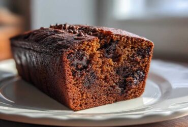 Close-up of a slice of moist chocolate chip banana bread recipe, showing melted chocolate chunks inside.