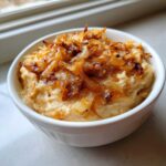 Close-up of creamy caramelized onion dip topped generously with golden brown caramelized onions in a white bowl.