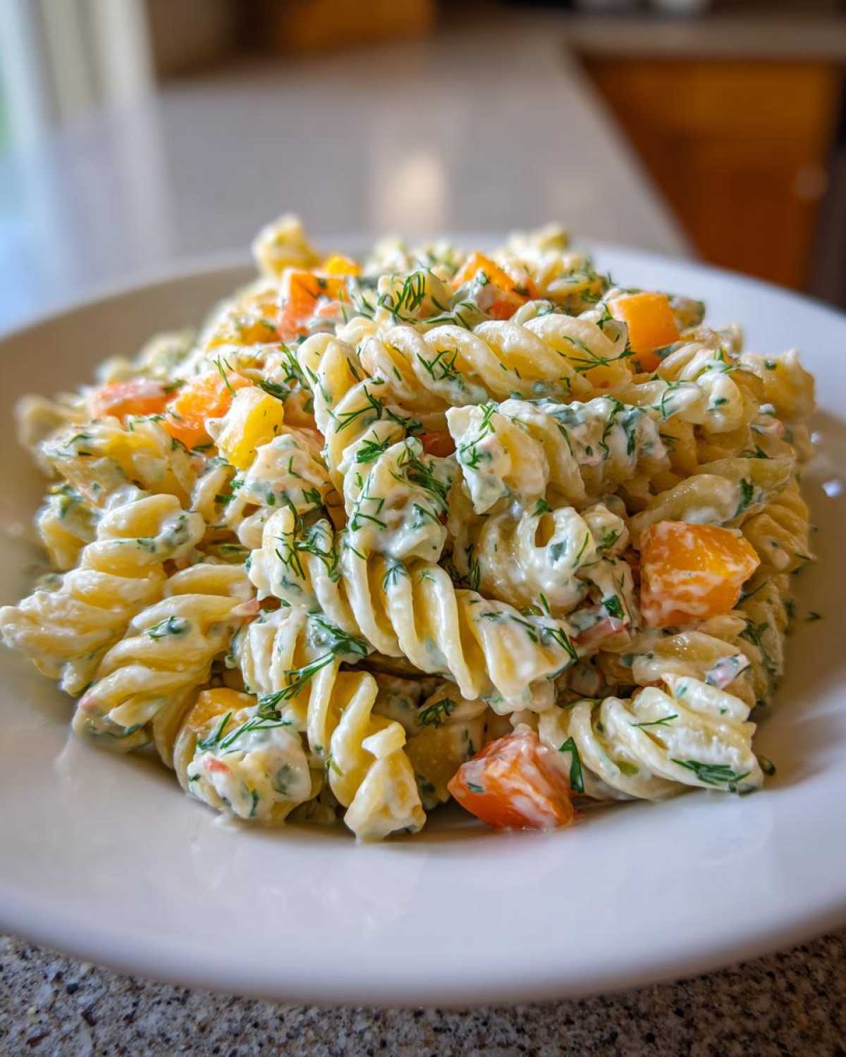 Close-up of creamy pickle pasta salad made with rotini pasta, orange chunks, and fresh dill.