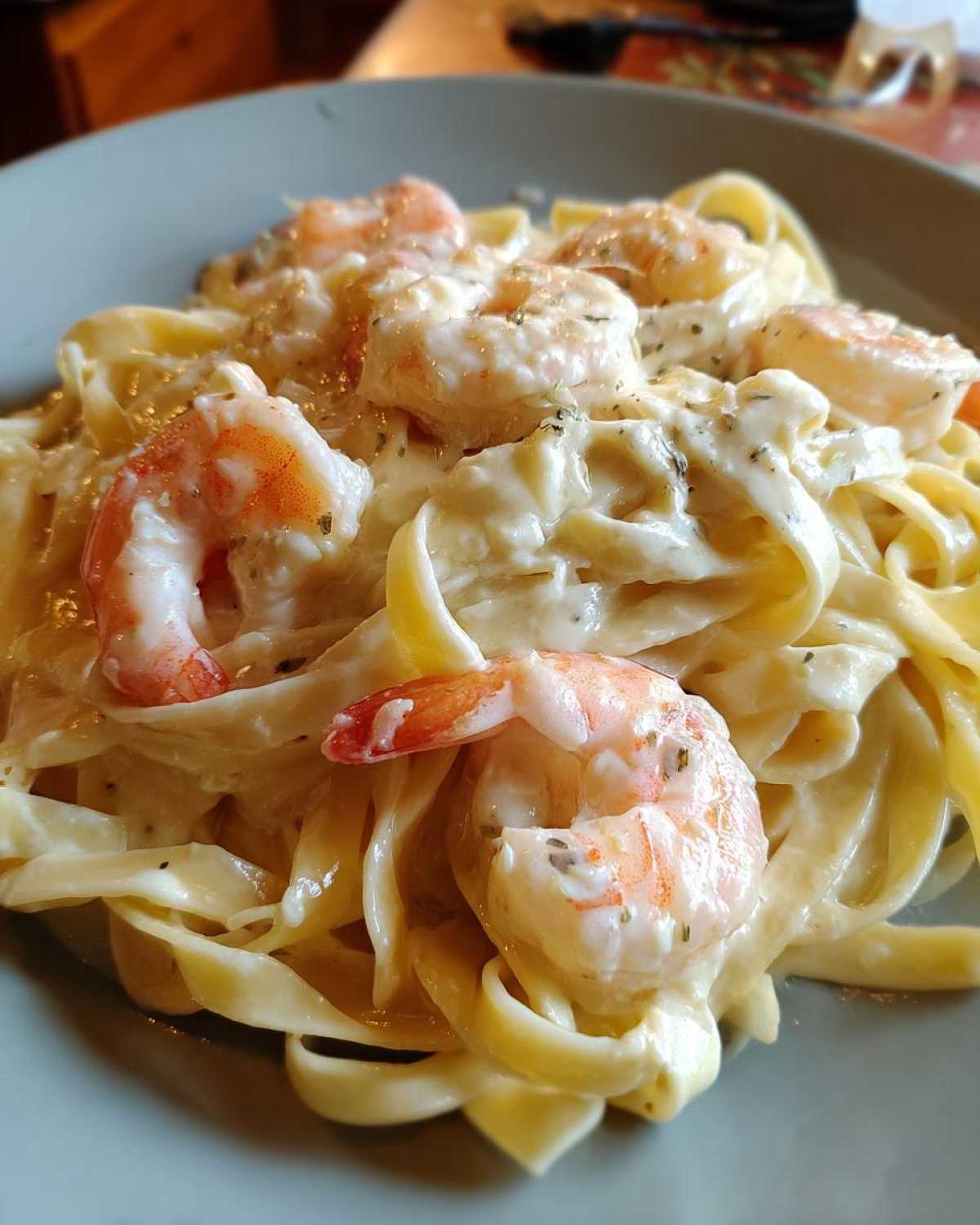 Close-up of creamy shrimp alfredo featuring large pink shrimp tossed with fettuccine pasta in a rich white sauce.