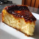 A close-up slice of creamy creme brulee cheesecake with a dark caramelized sugar top.