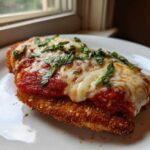 A perfectly cooked piece of chicken parmesan recipe, breaded and topped with marinara sauce, melted mozzarella, and fresh basil.