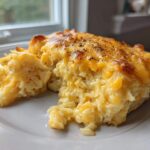 A close-up serving of creamy crockpot cheesy potatoes with a golden, bubbly, and seasoned cheese crust.