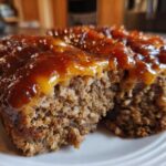Close-up of a moist slice of crockpot french onion meatloaf topped with a thick, glossy brown glaze.