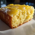 Close-up of a moist slice of fudgy Lemon Brownies topped with a thick, glossy lemon glaze.
