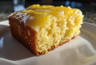 Close-up of a moist slice of fudgy Lemon Brownies topped with a thick, glossy lemon glaze.