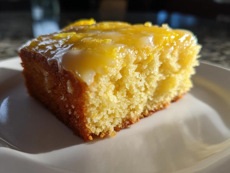 Close-up of a moist slice of fudgy Lemon Brownies topped with a thick, glossy lemon glaze.