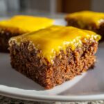 Close-up of a fudgy square of Lemon Brownies topped with a thick, shiny yellow lemon glaze.