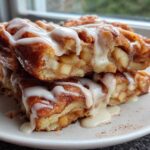 Two stacked baked apple fritters generously drizzled with white vanilla glaze, showing chunks of apple inside.