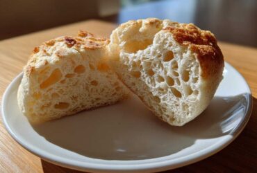 Close-up of homemade English muffins split in half showing the signature open, airy crumb structure.