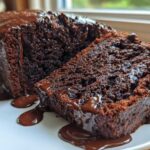 Close-up of a rich, dark slice of hot fudge brownie bread covered in dripping chocolate glaze.