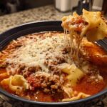 A spoonful of rich instant pot lasagna soup showing melted, stretchy mozzarella cheese being lifted from the bowl.