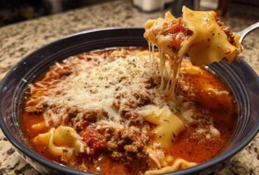 A spoonful of rich instant pot lasagna soup showing melted, stretchy mozzarella cheese being lifted from the bowl.