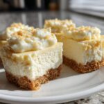 Four perfect no-bake mini cheesecake bites with graham cracker crusts and whipped topping on a white plate.