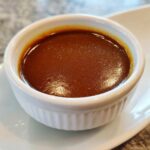 Close-up of rich, dark homemade brown gravy served in a small white fluted ramekin.