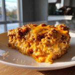 A hearty square serving of baked sausage cheese dip, topped with melted cheddar cheese.