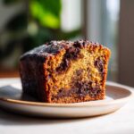 A moist slice of chocolate chip banana bread, rich with melted chocolate chunks, dusted with powdered sugar.