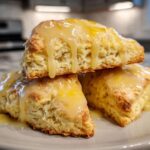 Three soft lemon scones stacked and drizzled with a thick, shiny lemon glaze.