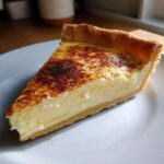 A close-up slice of amazing custard pie featuring a creamy yellow filling and a beautifully torched, caramelized top.