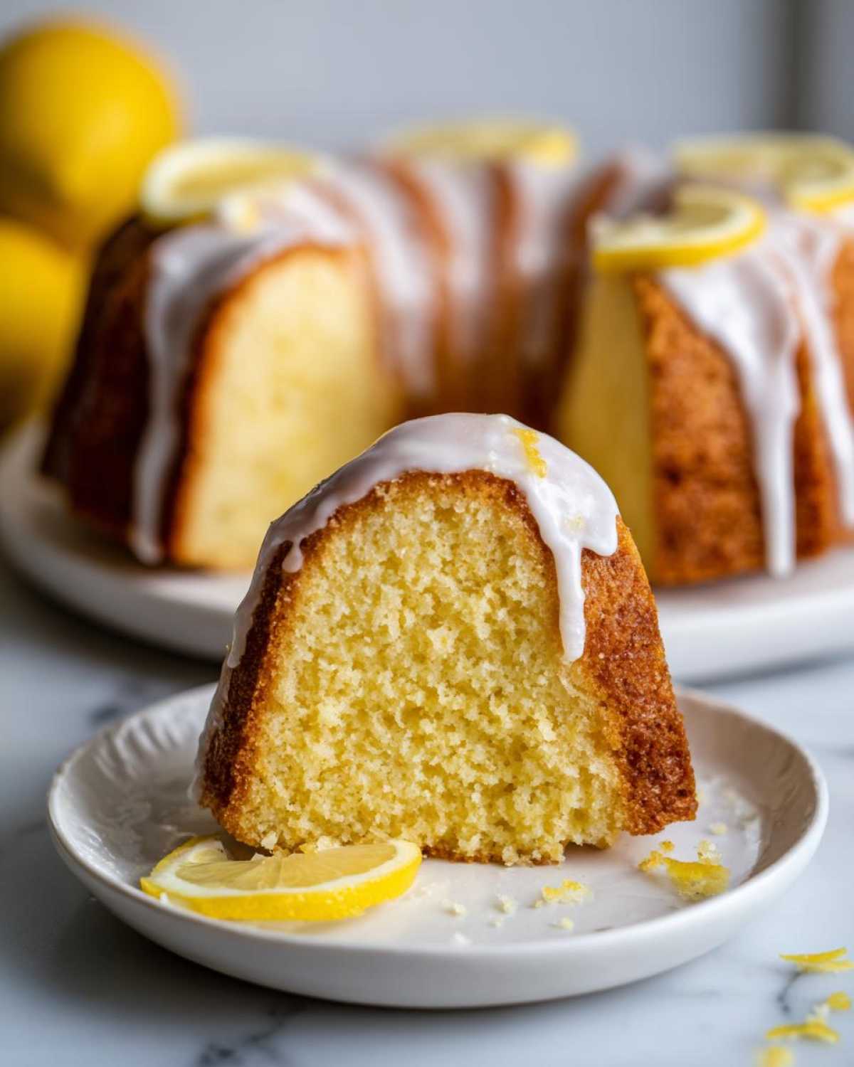 Close-up of a slice of amazing lemon pound cake topped with white glaze and a lemon slice.