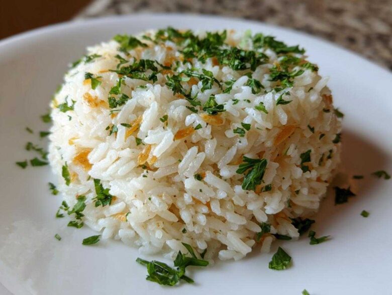 Close-up of a perfectly molded serving of fluffy rice pilaf topped with fresh chopped parsley and visible toasted pasta pieces.