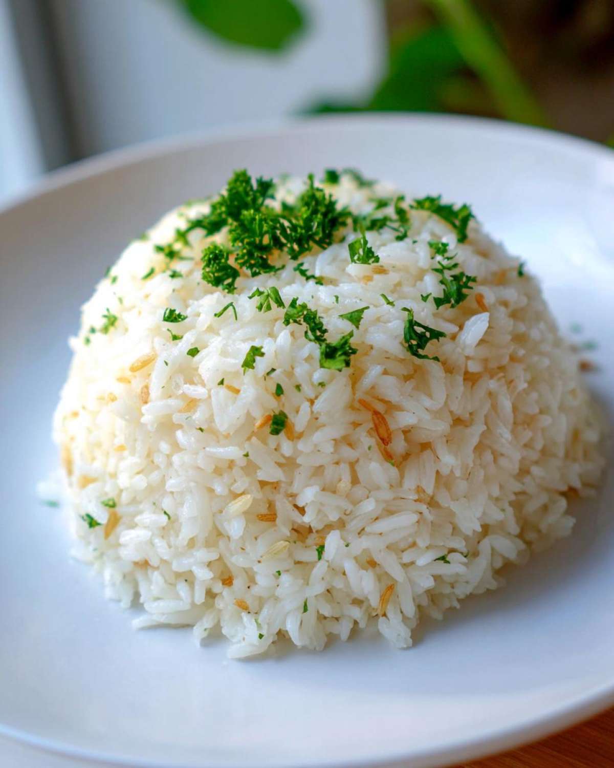 A perfectly molded serving of fluffy white rice pilaf garnished with fresh chopped parsley.