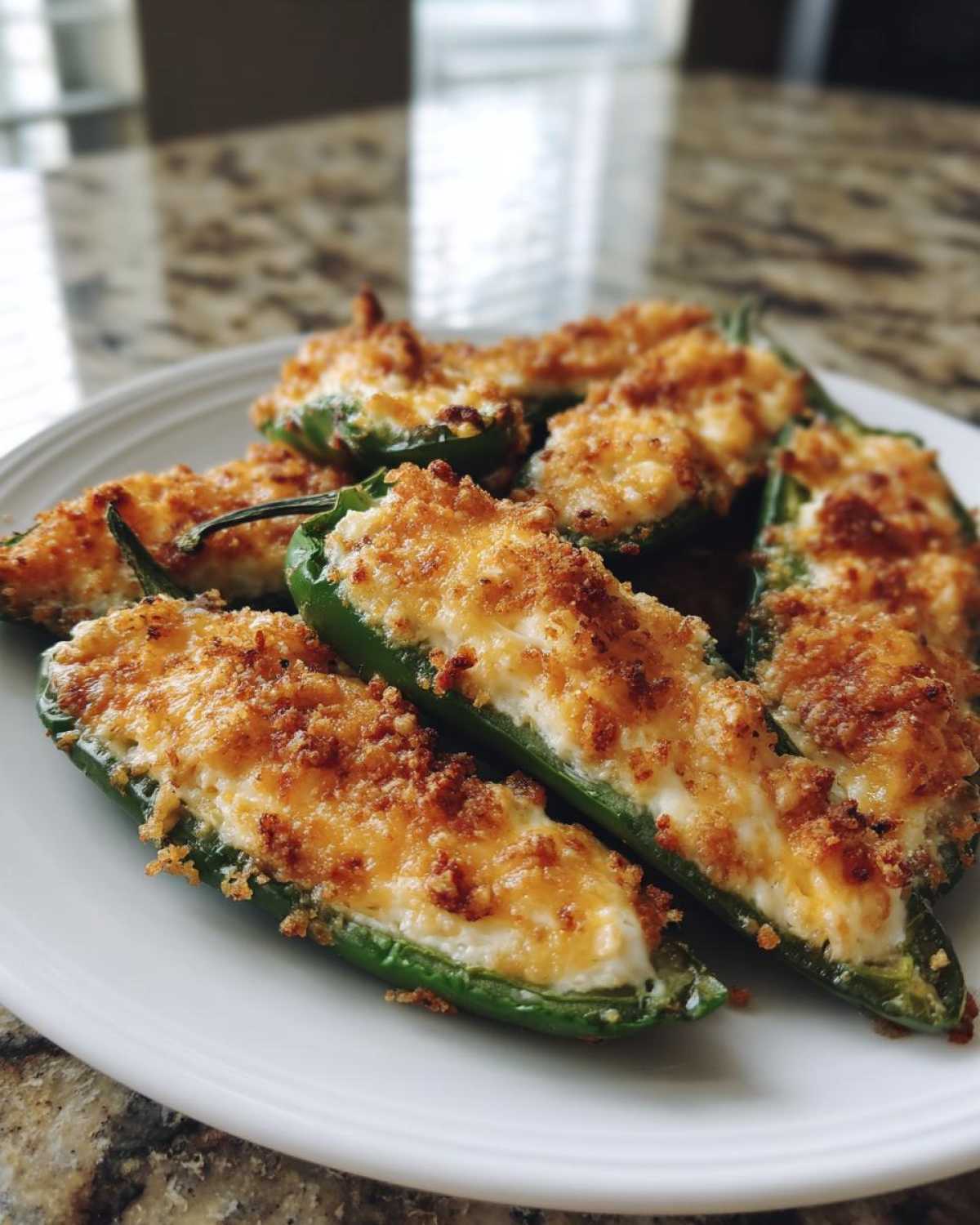 A plate of freshly baked jalapeño poppers filled with creamy cheese and topped with golden brown breadcrumbs.