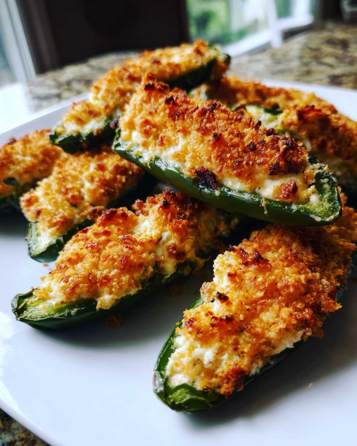A pile of freshly baked jalapeño poppers, stuffed with creamy cheese and topped with golden, crispy breadcrumbs.