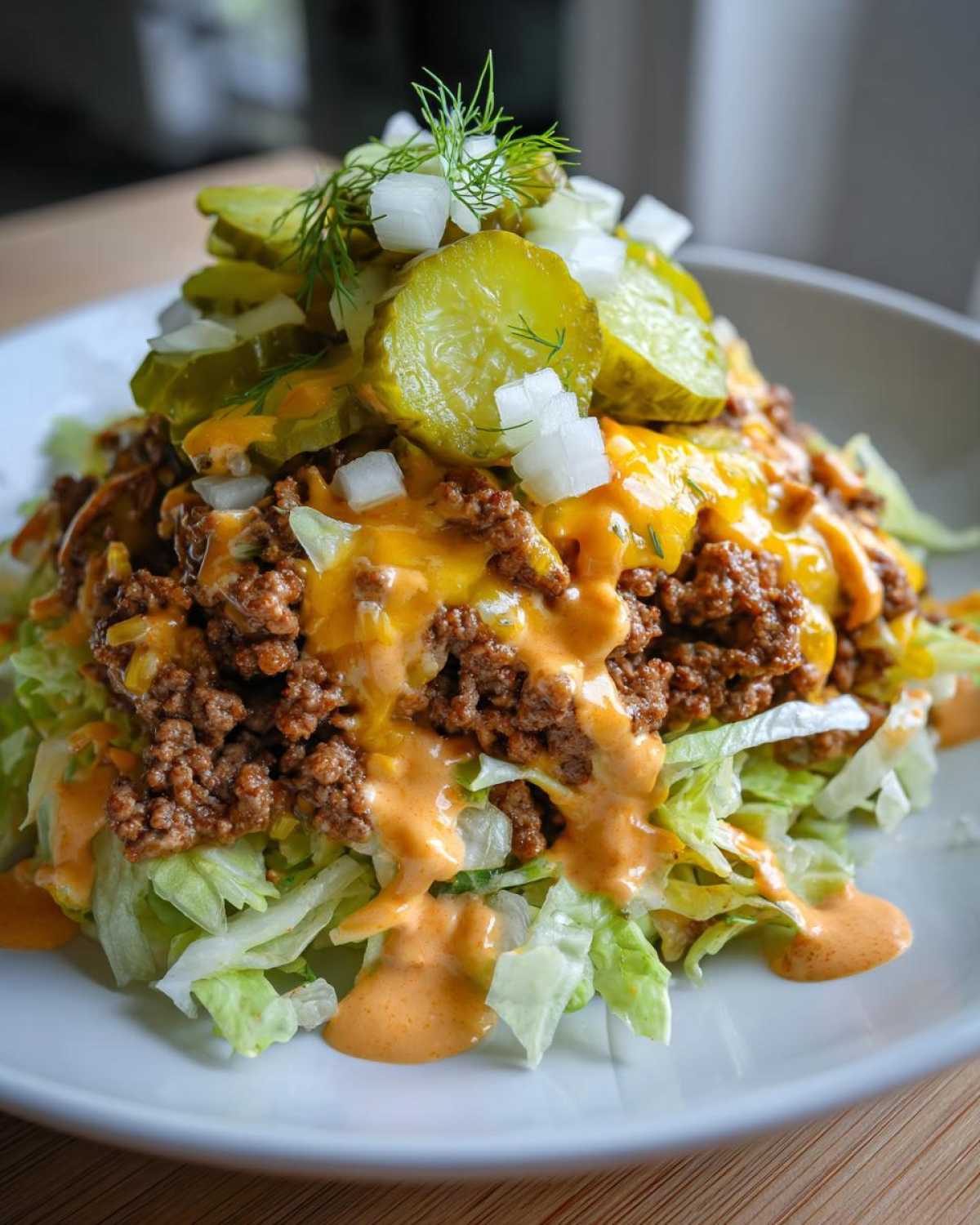 Close-up of a delicious cheeseburger bowl featuring seasoned ground beef, melted cheese, lettuce, pickles, and sauce.