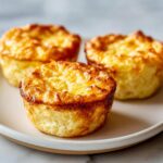 Three golden brown cottage cheese egg cups starbucks style arranged on a light plate.