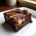 A square slice of rich, dark Cottage Cheese Microwave Brownie featuring a creamy, light-colored swirl on top.