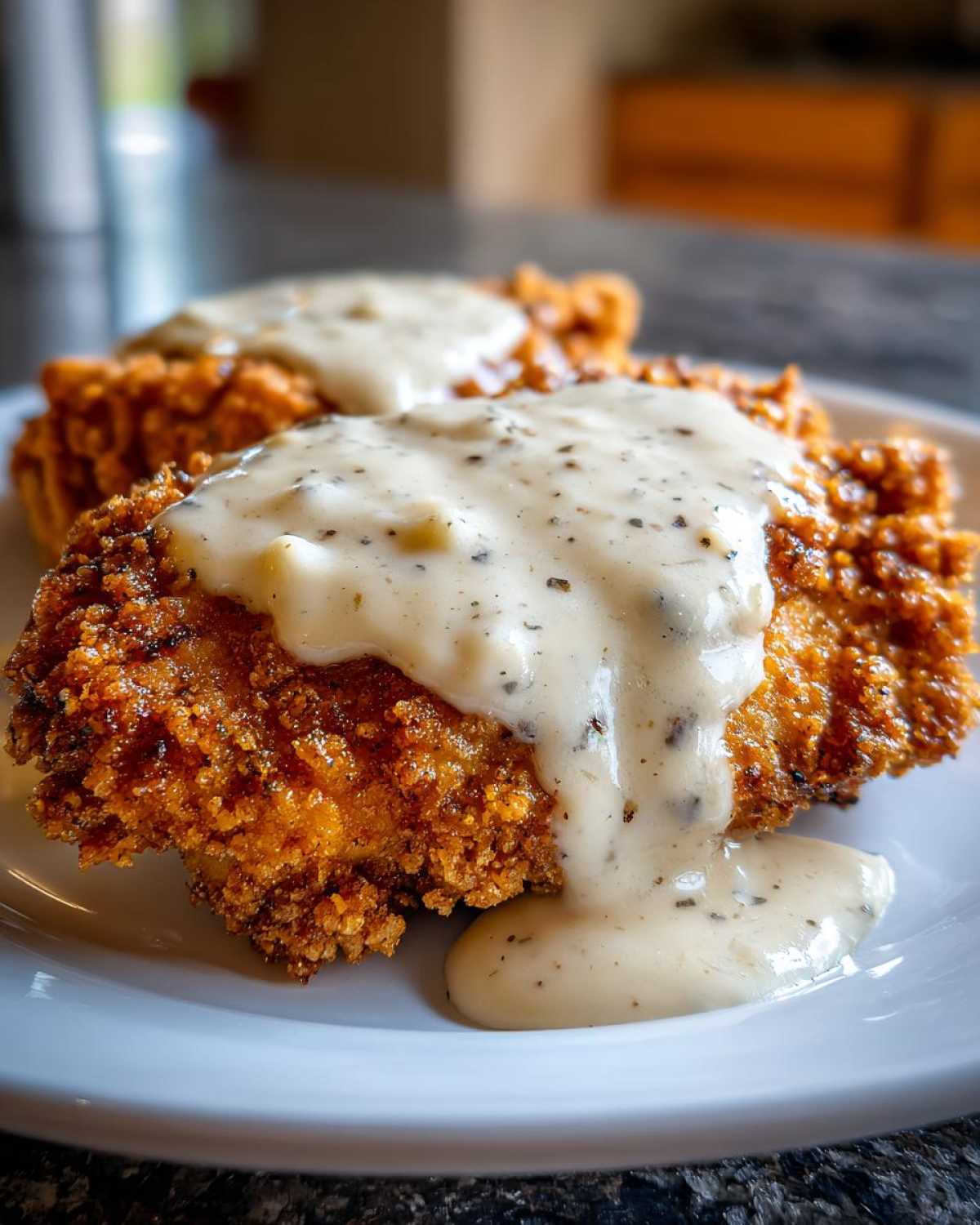 Two portions of crispy, golden brown chicken fried steak smothered in thick, peppered white country gravy.