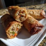 Close-up of crispy fried egg roll cut in half, revealing savory ground meat and vegetable filling.