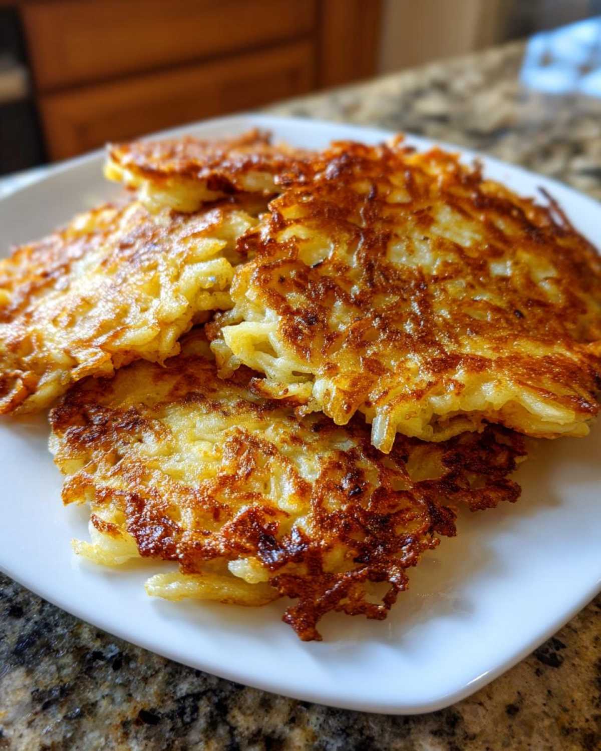 A stack of golden brown, crispy potato pancakes showing shredded texture, ready to eat.
