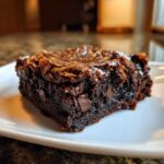 Close-up of a rich, fudgy square of black bean brownies topped with a shiny crust and visible chocolate chips.