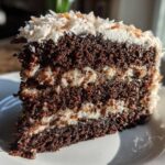 Close-up of a moist slice of german chocolate cake recipe showing dark chocolate layers and coconut pecan filling.