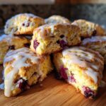 A stack of freshly baked blueberry scones drizzled with white glaze, showcasing their moist interior.