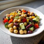 Close-up of a vibrant, high protein bean salad featuring chickpeas, kidney beans, cucumber, and bell peppers.