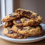 A stack of freshly baked homemade chocolate chip cookies with melted chocolate chips and coarse salt.