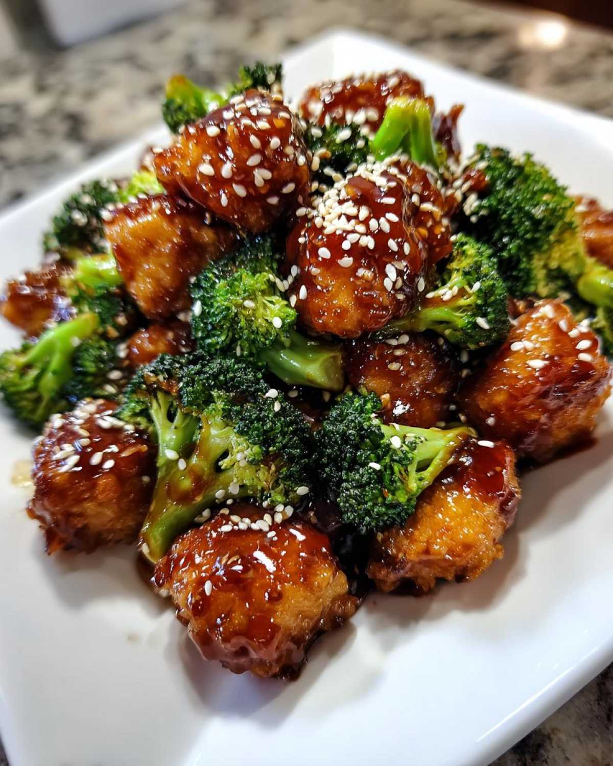 Close-up of glazed chicken and broccoli pieces topped with sesame seeds, perfect for chicken and broccoli recipes.
